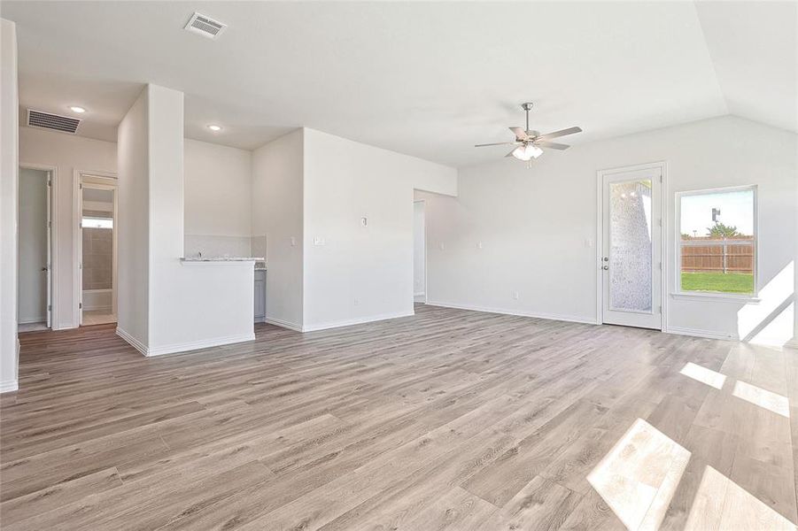 Unfurnished living room featuring light hardwood / wood-style floors, lofted ceiling, and ceiling fan