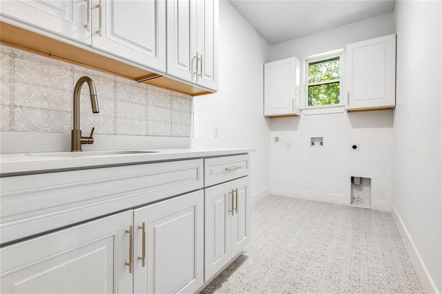 Washroom with sink, cabinets, hookup for a washing machine, hookup for an electric dryer, and hookup for a gas dryer