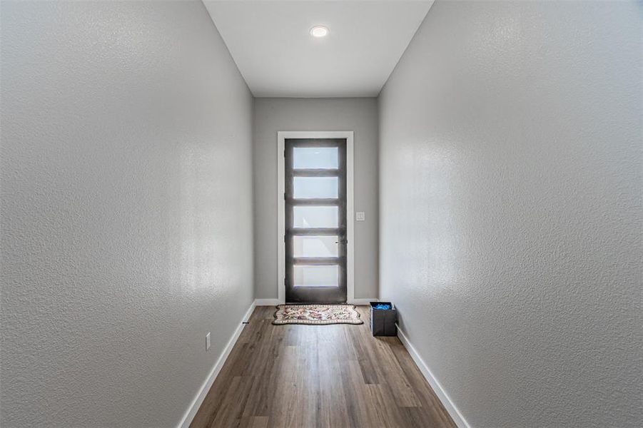Doorway with wood finished floors and a textured wall