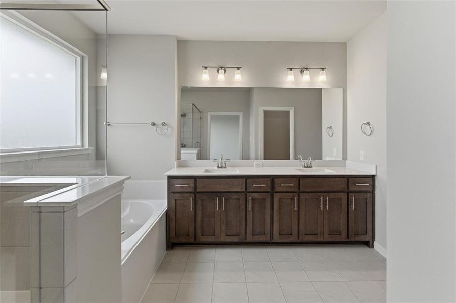 Full bathroom featuring double vanity, a shower stall, a bath, and light tile patterned flooring