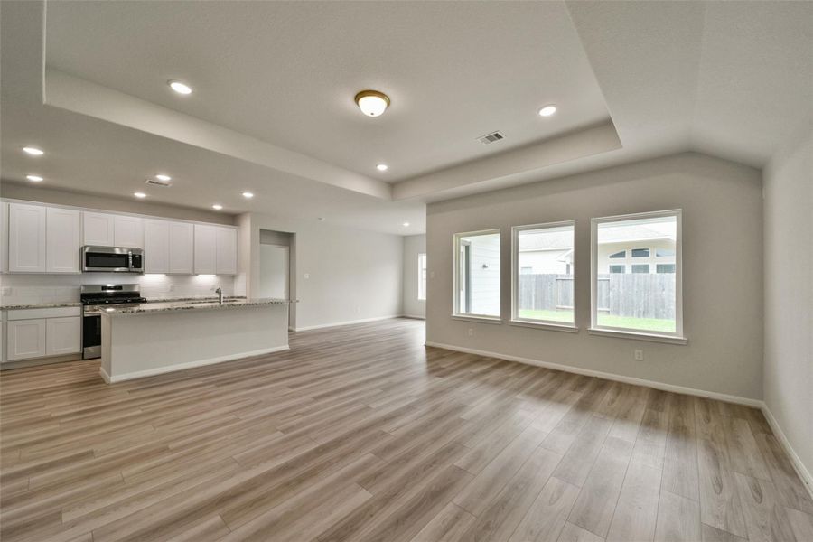 Bright, open-concept living space featuring a gourmet granite kitchen and modern wood flooring.