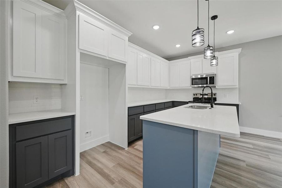 Kitchen featuring stainless steel microwave, light wood-style floors, light countertops, decorative backsplash, and recessed lighting