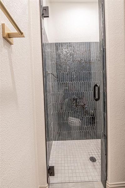 Bathroom featuring a textured wall and a stall shower Bathroom featuring a textured wall and a stall shower