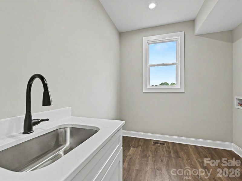 Functional and stylish laundry room offers added convenience with a utility sink, durable flooring, and plenty of space for storage and organization.