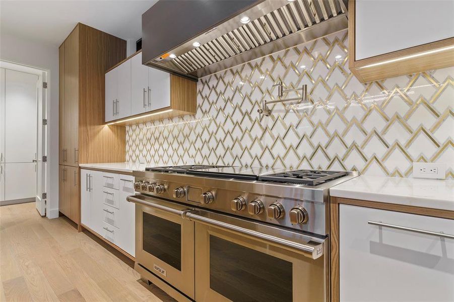 Kitchen with range with two ovens, light hardwood / wood-style flooring, decorative backsplash, custom range hood, and white cabinetry