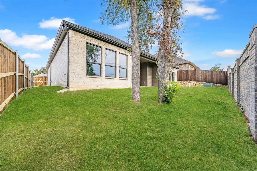 Rear view of property featuring a fenced backyard and brick siding