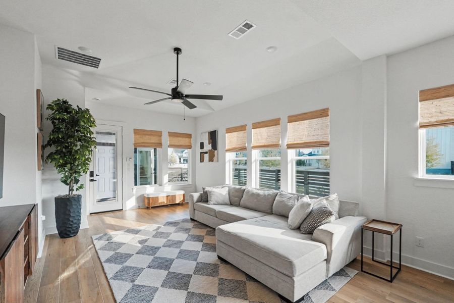 Light-filled living space with soaring ceilings, expansive windows, and warm wood flooring creating an inviting, upscale atmosphere. The open layout flows effortlessly to the outdoors, offering a bright and airy retreat perfect for relaxing or gathering.