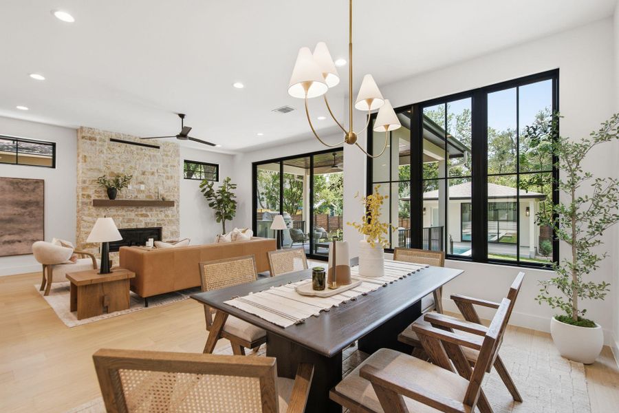 A spacious open-concept dining area transitions seamlessly into the living room alongside large black-framed windows.