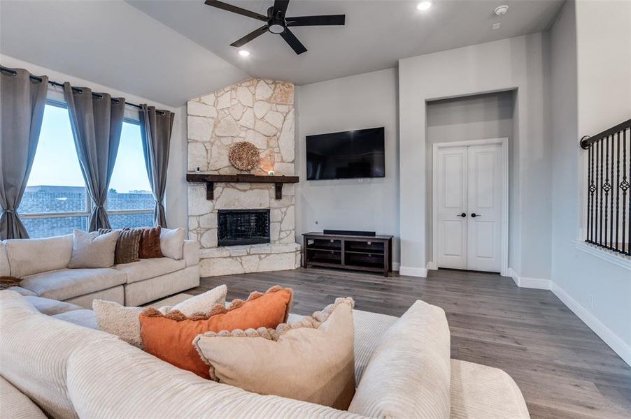 Living room featuring a ceiling fan, lofted ceiling, wood finished floors, a fireplace, and recessed lighting Living room featuring a ceiling fan, lofted ceiling, wood finished floors, a fireplace, and recessed lighting