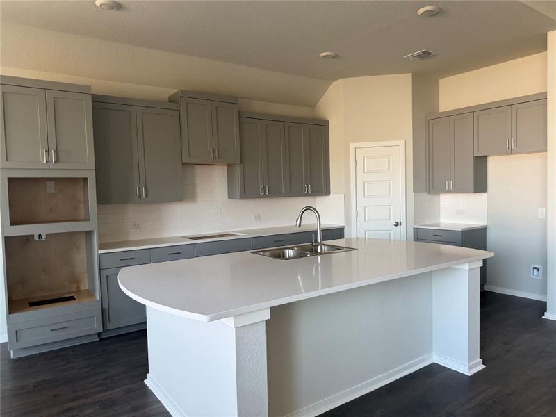 Streamlined cabinetry and a prominent island highlight this modern culinary space with wood flooring.