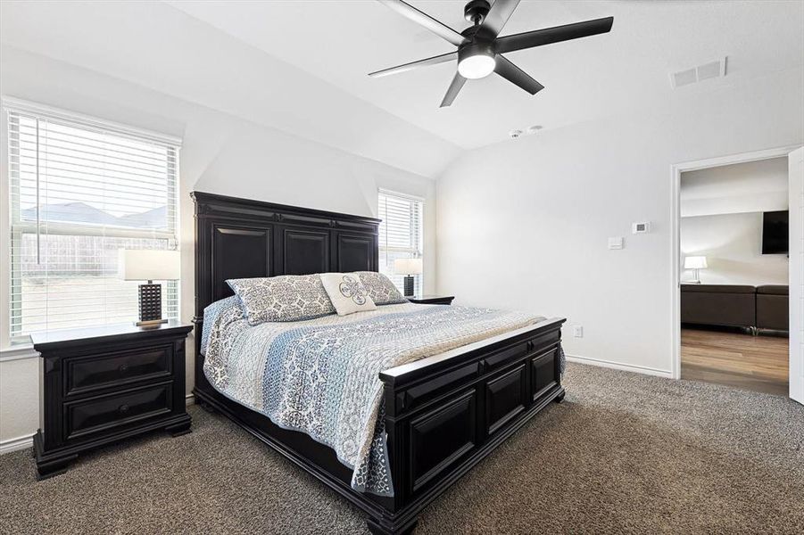 Carpeted bedroom with lofted ceiling and ceiling fan