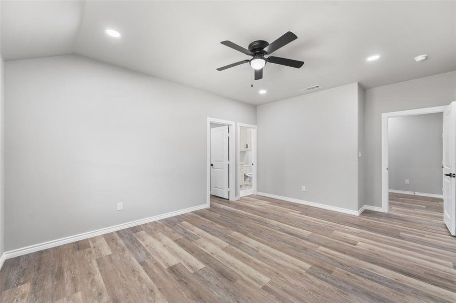 Spacious interior featuring wood-finish flooring, light gray wall tones, and recessed lighting Spacious interior featuring wood-finish flooring, light gray wall tones, and recessed lighting
