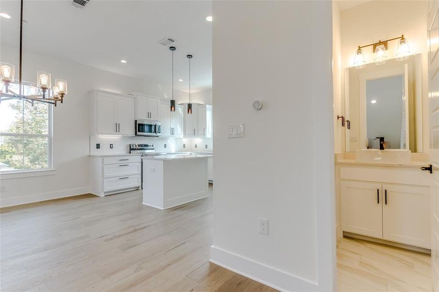 Kitchen with appliances with stainless steel finishes, backsplash, pendant lighting, white cabinets, and a center island