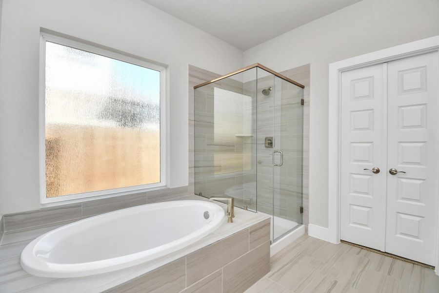 Indulge in a spa-like retreat within the confines of this primary bathroom. Delight in a spacious walk-in shower enveloped in stylish tile surround and unwind in a separate garden tub adorned with custom detailing. Indulge in a spa-like retreat within the confines of this primary bathroom. Delight in a spacious walk-in shower enveloped in stylish tile surround and unwind in a separate garden tub adorned with custom detailing.