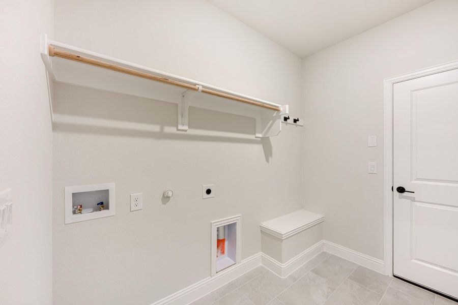 Laundry room with wall-mounted clothing rod, built-in bench, washer hookups, and tile floor Laundry room with wall-mounted clothing rod, built-in bench, washer hookups, and tile floor