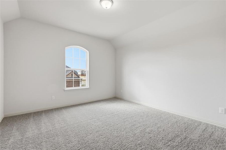 Unfurnished room with lofted ceiling and carpet flooring Unfurnished room with lofted ceiling and carpet flooring