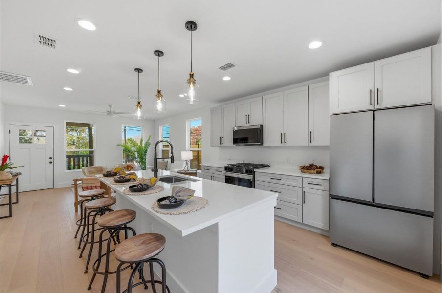 Kitchen with stainless steel appliances, light wood-style flooring, white cabinetry, pendant lighting, and recessed lighting