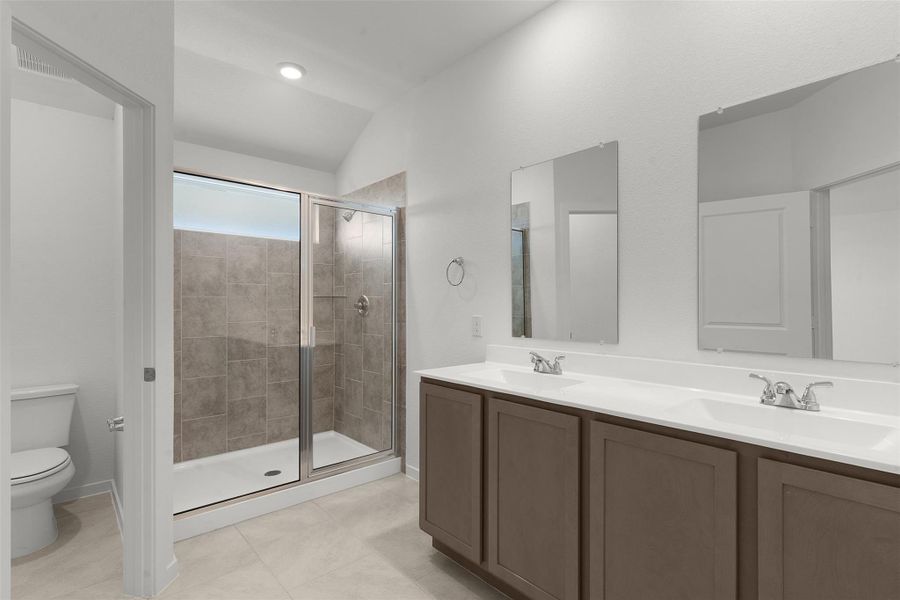 Full bath with double vanity, a stall shower, light tile patterned floors, and lofted ceiling