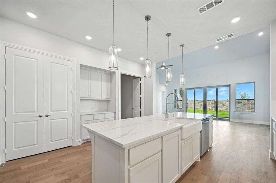 Kitchen featuring light stone countertops, recessed lighting, white cabinets, light wood-style flooring, and an island with sink Kitchen featuring light stone countertops, recessed lighting, white cabinets, light wood-style flooring, and an island with sink