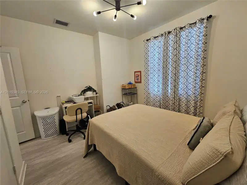 Wood-finish flooring, multi-arm industrial style ceiling fixture, and a standard interior door