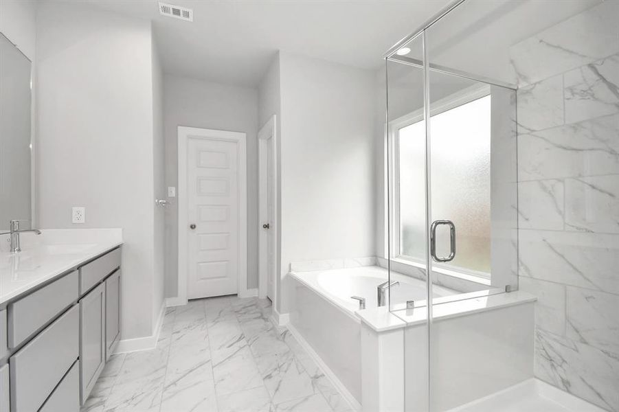 This additional view of the primary bath features a walk-in shower with the tile surround and separate garden tub perfect for soaking after a long day. Sample photo of completed home with similar floor plan. As-built interior colors and selections may vary.