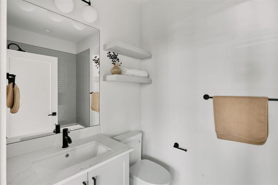 Modern bathroom featuring a white vanity with an integrated sink, a quartz-finish countertop, and matte black fixtures Modern bathroom featuring a white vanity with an integrated sink, a quartz-finish countertop, and matte black fixtures