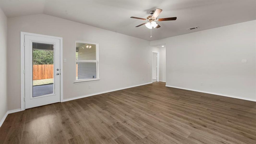Spacious interior room featuring wood-finish flooring, vaulted ceilings, and a ceiling fan with integrated lighting Spacious interior room featuring wood-finish flooring, vaulted ceilings, and a ceiling fan with integrated lighting