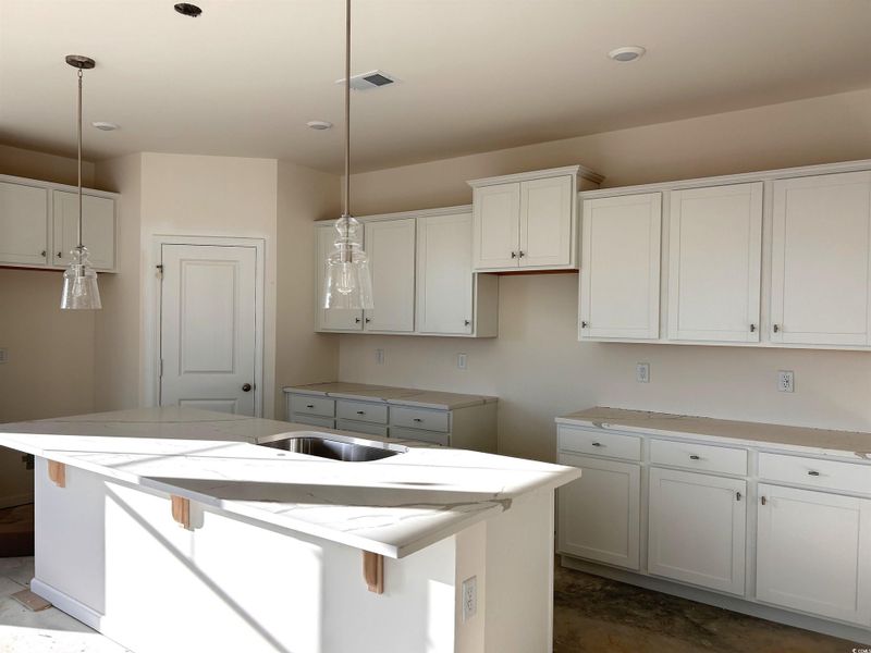 Kitchen featuring white cabinetry, a breakfast bar, a center island with sink, pendant lighting, and recessed lighting