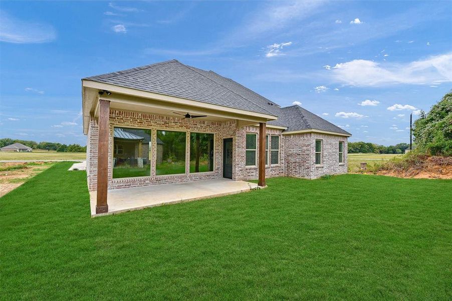 Rear view of property with a lawn and a patio