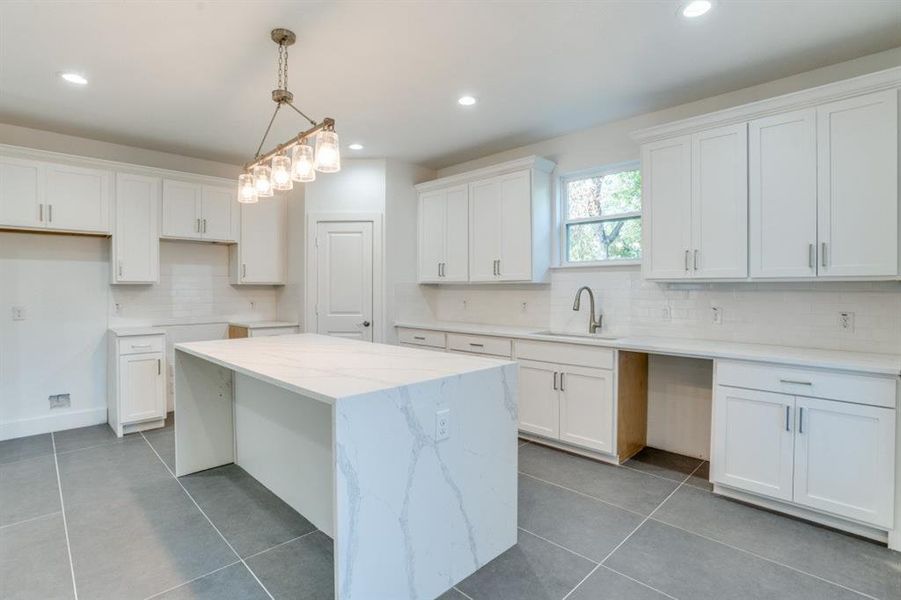 Kitchen with white cabinetry, sink, pendant lighting, and a kitchen island