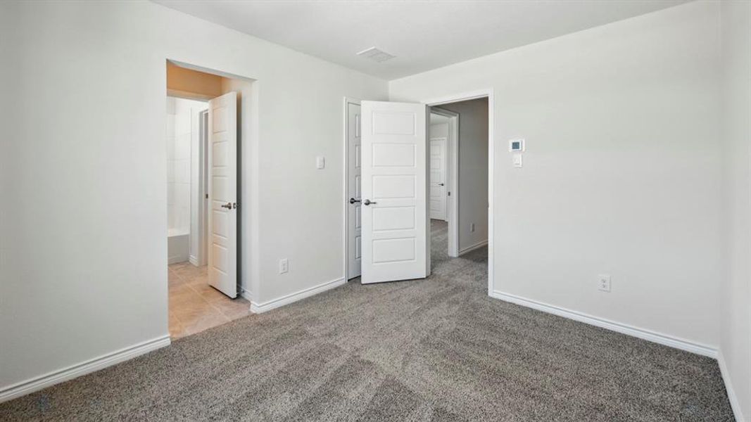 Unfurnished bedroom featuring light carpet and ensuite bathroom
