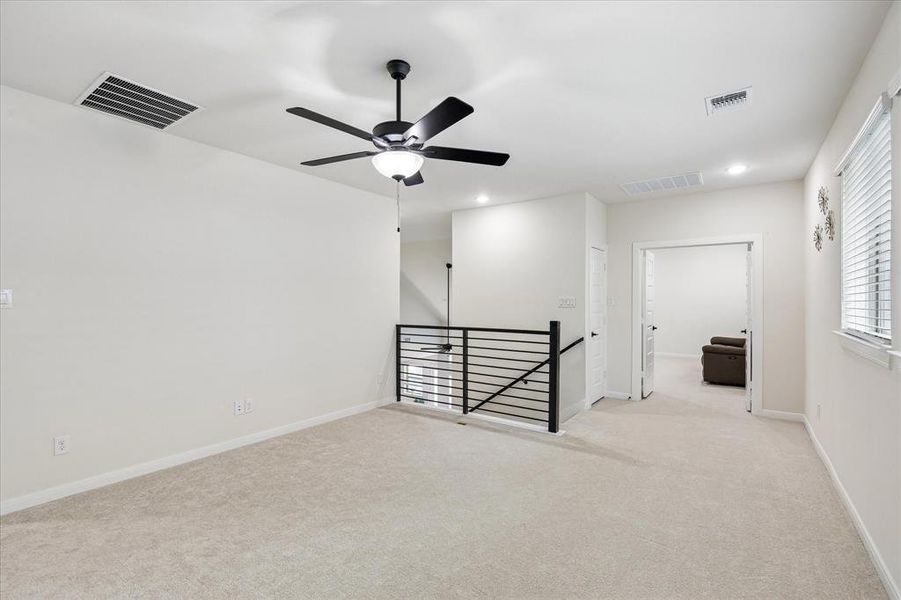 Spacious room featuring neutral carpeting, a ceiling fan, recessed lighting, and a white window with horizontal blinds Spacious room featuring neutral carpeting, a ceiling fan, recessed lighting, and a white window with horizontal blinds