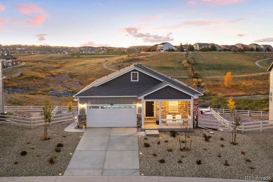 Charming ranch-style home with stone accents, inviting porch, and a view of the surrounding hills.