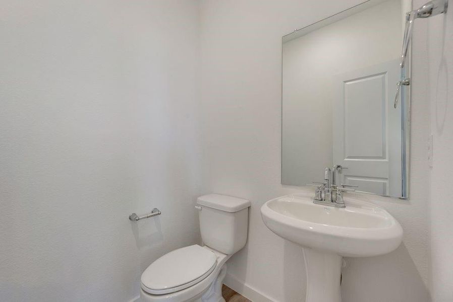Half bathroom with toilet and baseboards