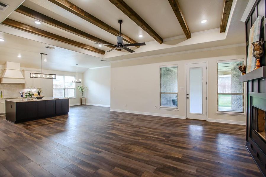 Unfurnished living room featuring a fireplace, a chandelier, ceiling fan, dark wood-type flooring, and beamed ceiling Unfurnished living room featuring a fireplace, a chandelier, ceiling fan, dark wood-type flooring, and beamed ceiling