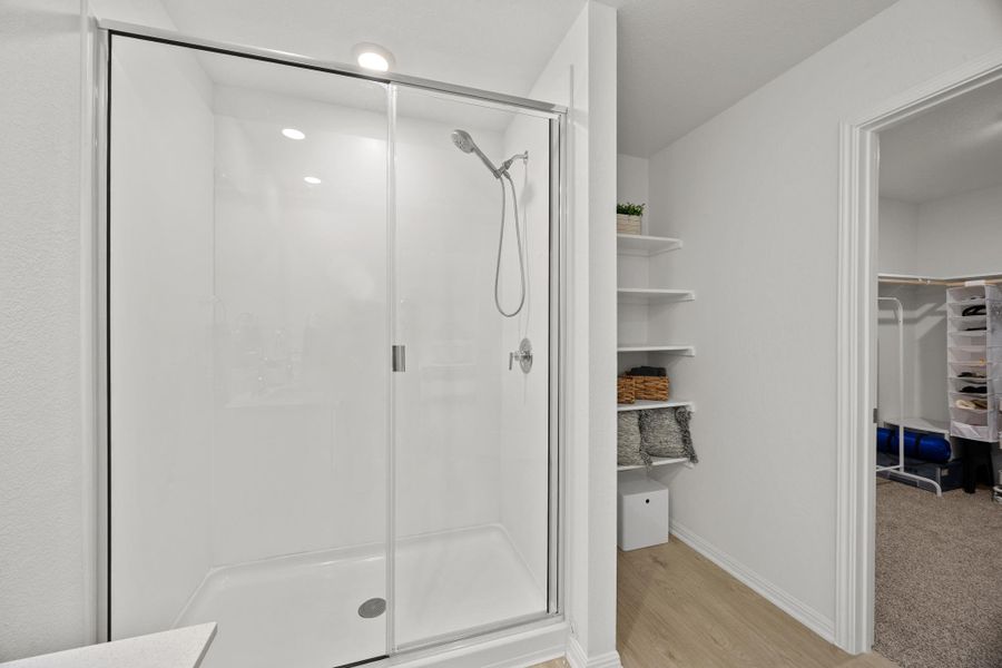 Bathroom featuring a stall shower, a walk in closet, and light wood-style floors