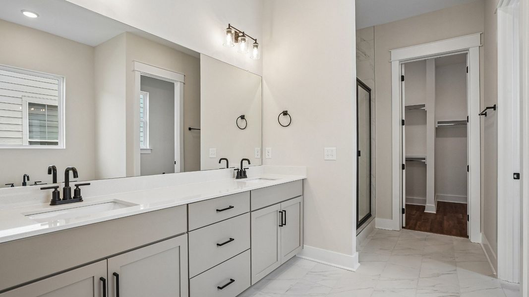 Primary bathroom with dual vanity, tile flooring, quartz countertops, shower, and walk-in closet