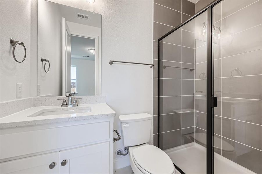 Bathroom featuring vanity with extensive cabinet space, a shower with shower door, and toilet