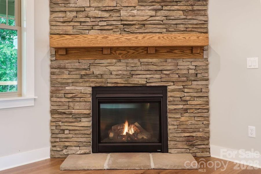 Switch controlled gas fireplace with floor to ceiling stone wall.
