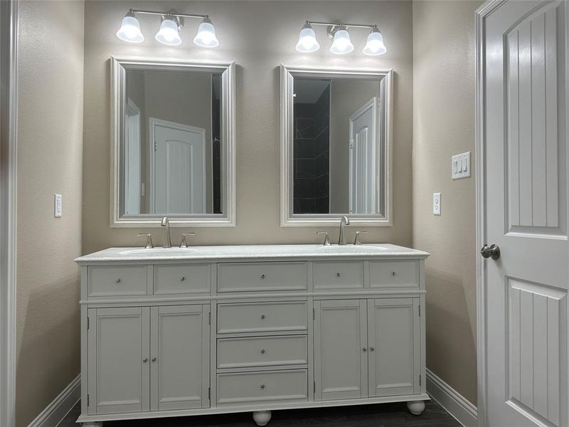 Full bath featuring baseboards and double vanity