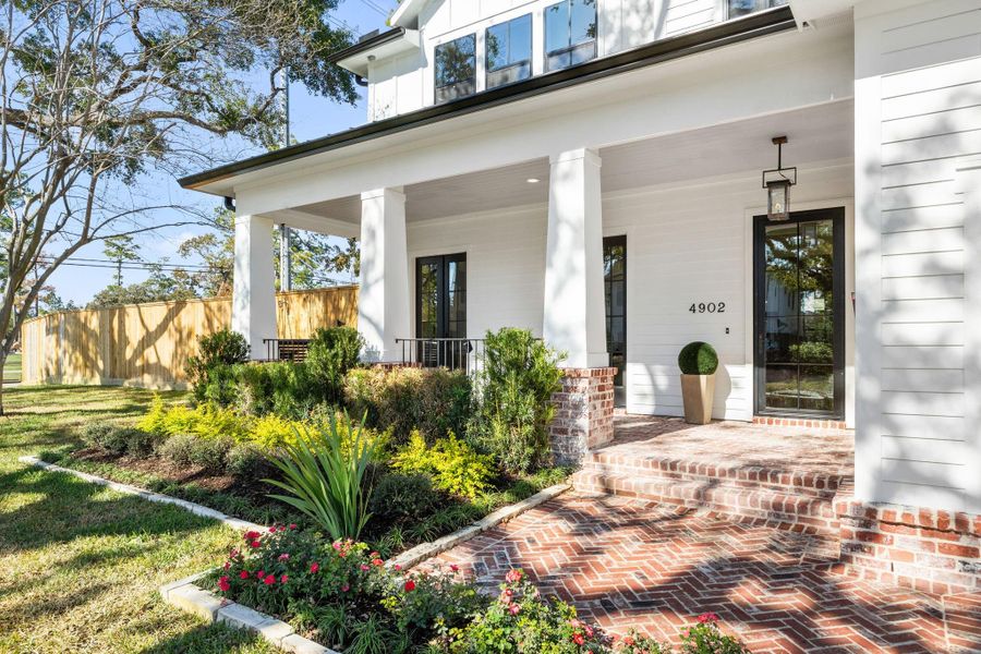 Designer landscaping and a herringbone brick front porch provide luxurious curb appeal.
