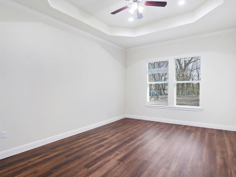 Spare room with ceiling fan, dark wood-style flooring, ornamental molding, and a tray ceiling Spare room with ceiling fan, dark wood-style flooring, ornamental molding, and a tray ceiling