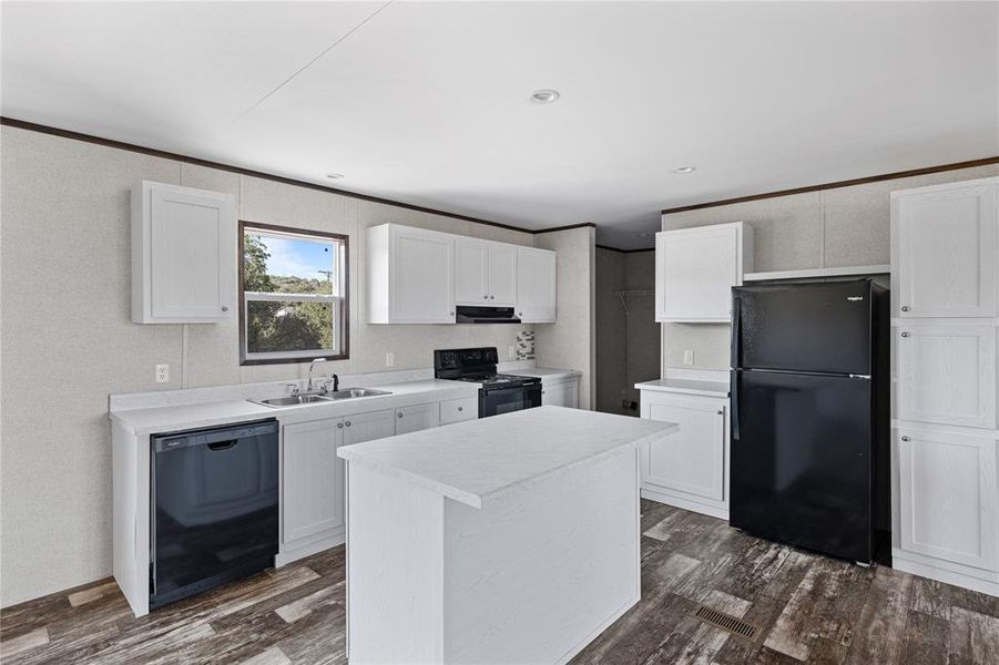 Kitchen with dark wood-type flooring, a kitchen island, white cabinets, sink, and black appliances