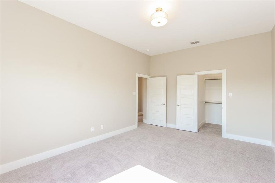 Unfurnished bedroom featuring light colored carpet, a spacious closet, and a closet