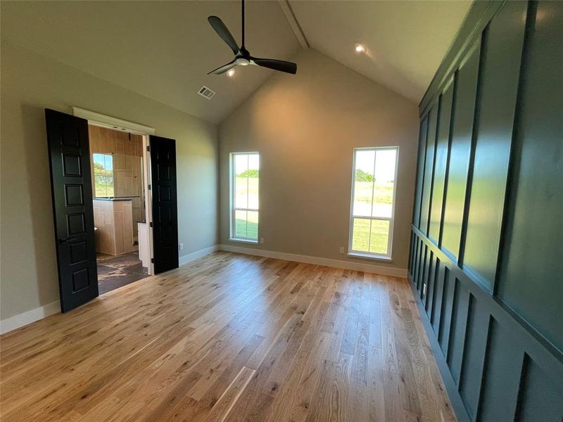 Spacious room featuring vaulted ceilings, light wood-finish flooring, and a modern ceiling fan