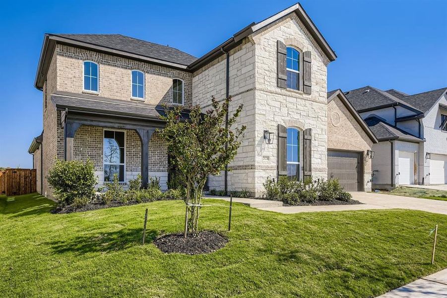 French country inspired facade featuring stone siding, a garage, and brick siding