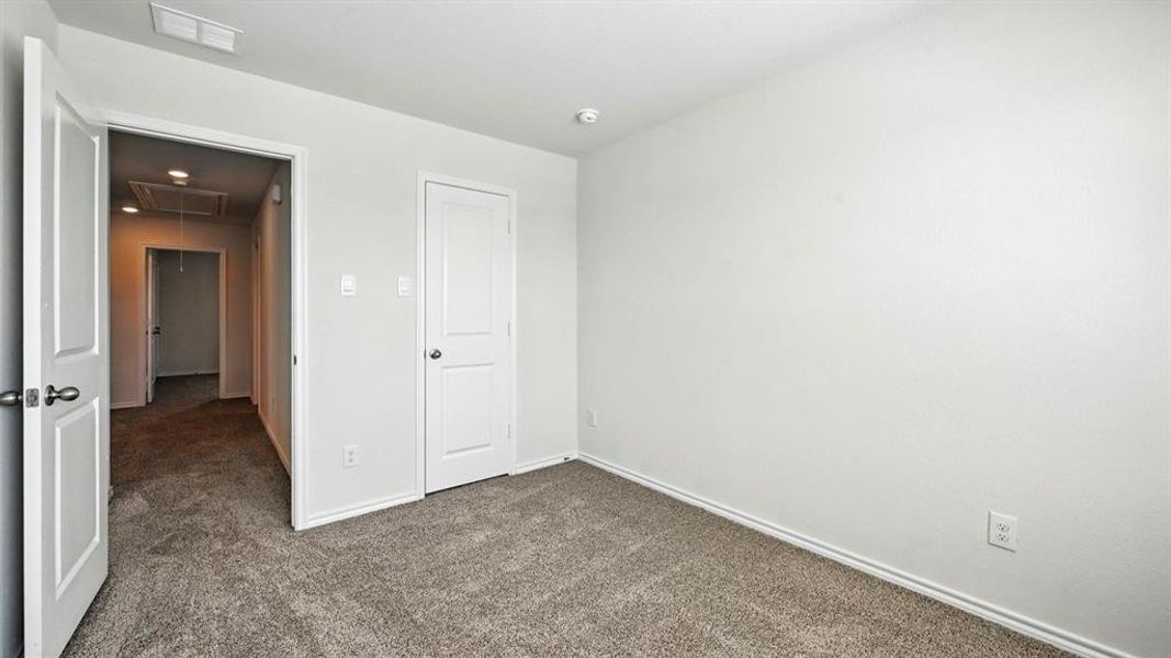 Unfurnished bedroom featuring dark carpet and attic access