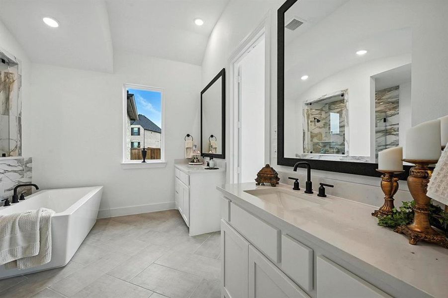 Full bathroom with two vanities, a freestanding bath, recessed lighting, a marble finish shower, and light tile patterned floors