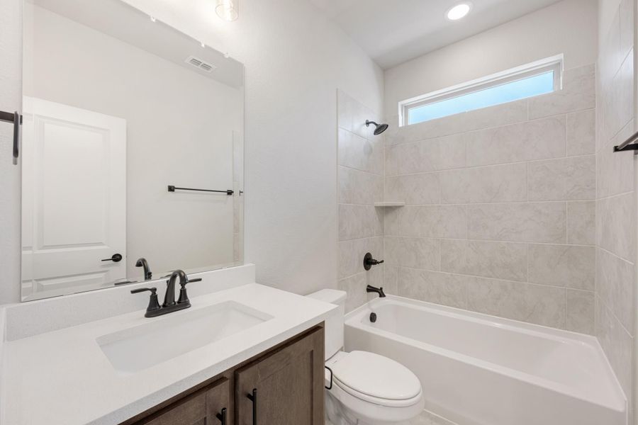 Bathroom with wood vanity, white countertop, tiled tub-shower combo, and matte black fixtures Bathroom with wood vanity, white countertop, tiled tub-shower combo, and matte black fixtures
