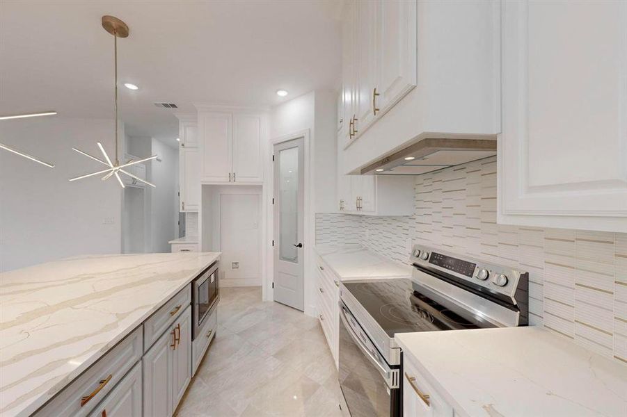 Kitchen with stainless steel appliances, light stone countertops, white cabinets, and recessed lighting